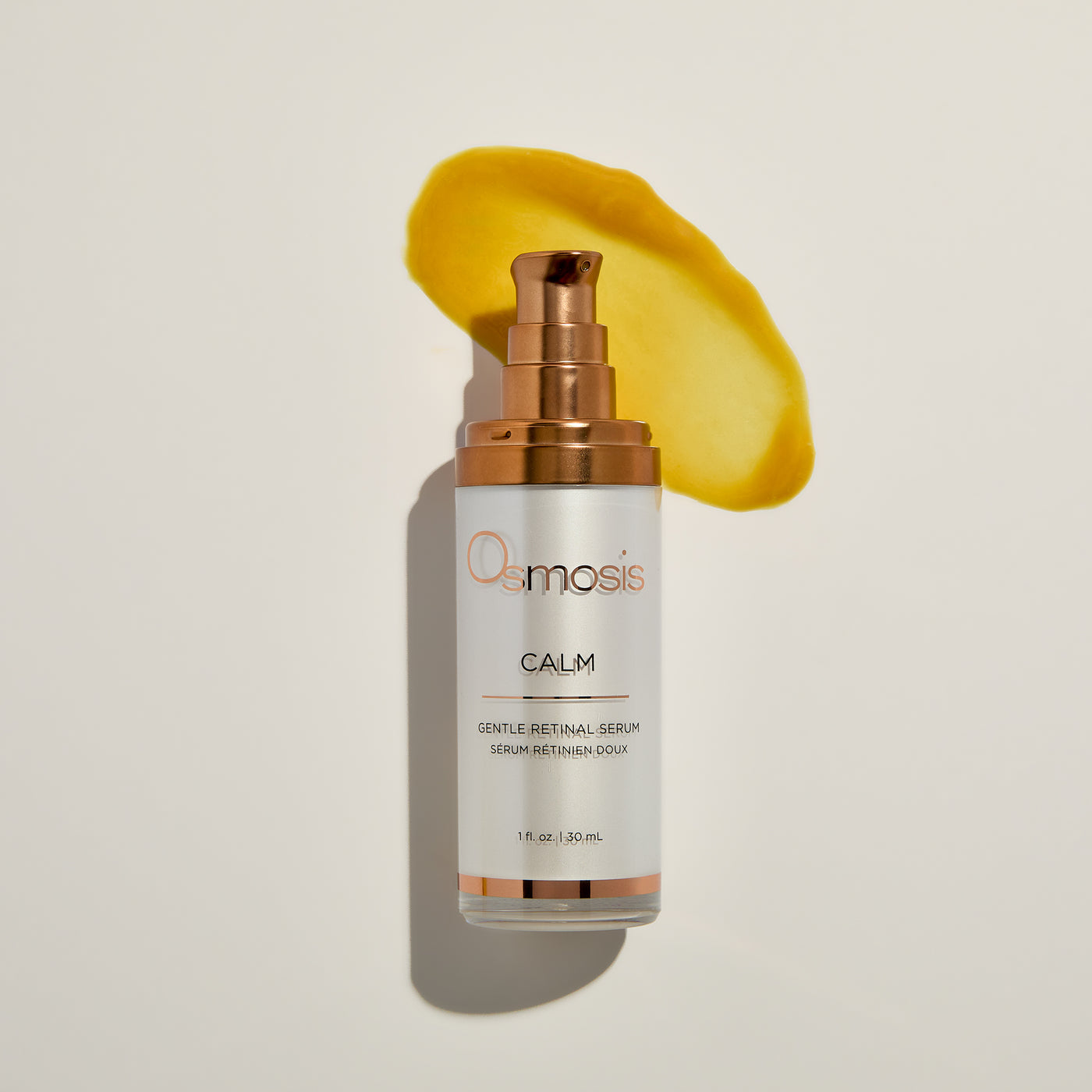 Osmosis Calm serum bottle with a yellow product smear on a light beige background