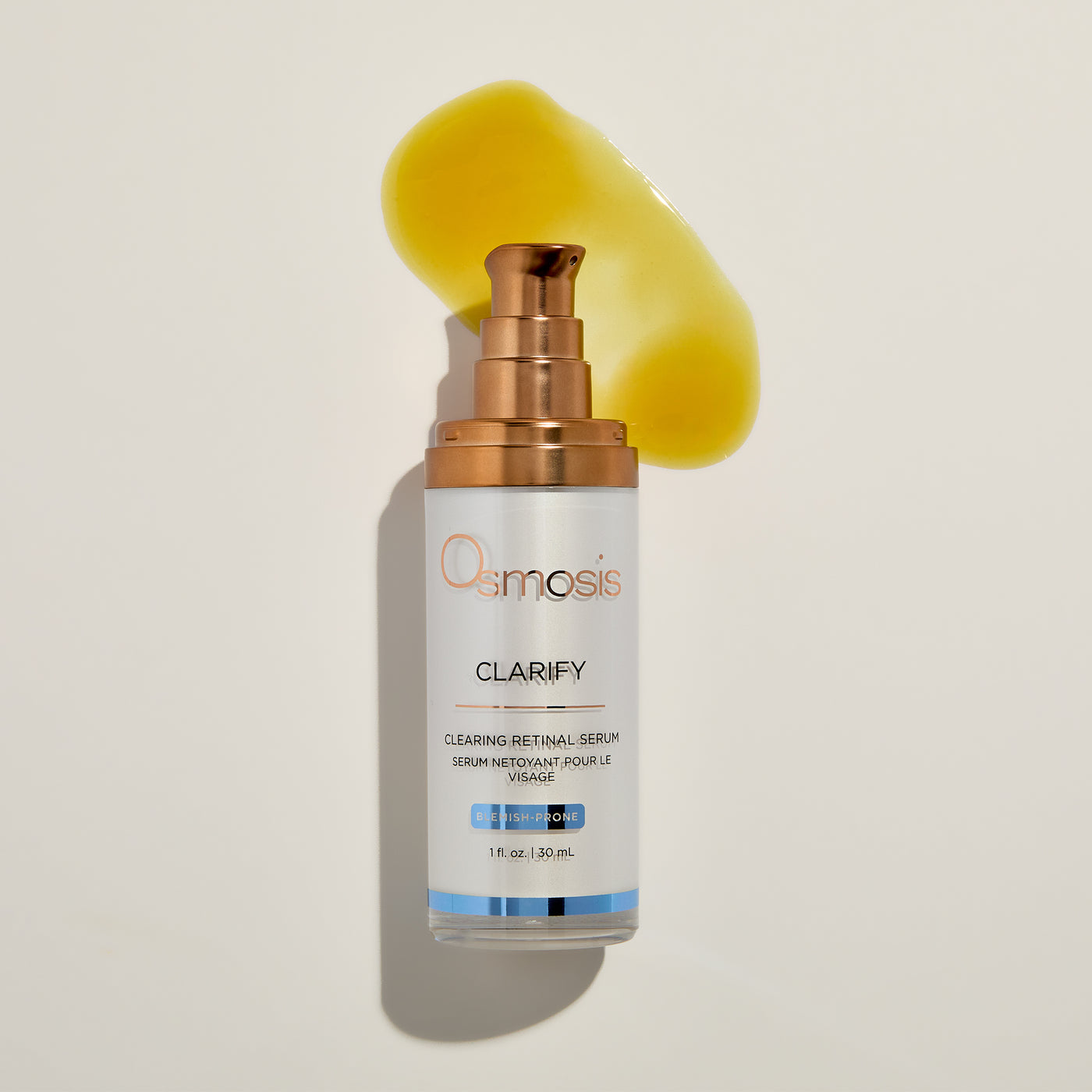 Osmosis Clarify serum bottle with a yellow product smear on a beige background