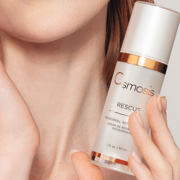 Osmosis Rescue skincare serum held by a hand with a neutral background