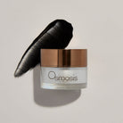 Osmosis Skincare jar with a black product smear on a light gray background