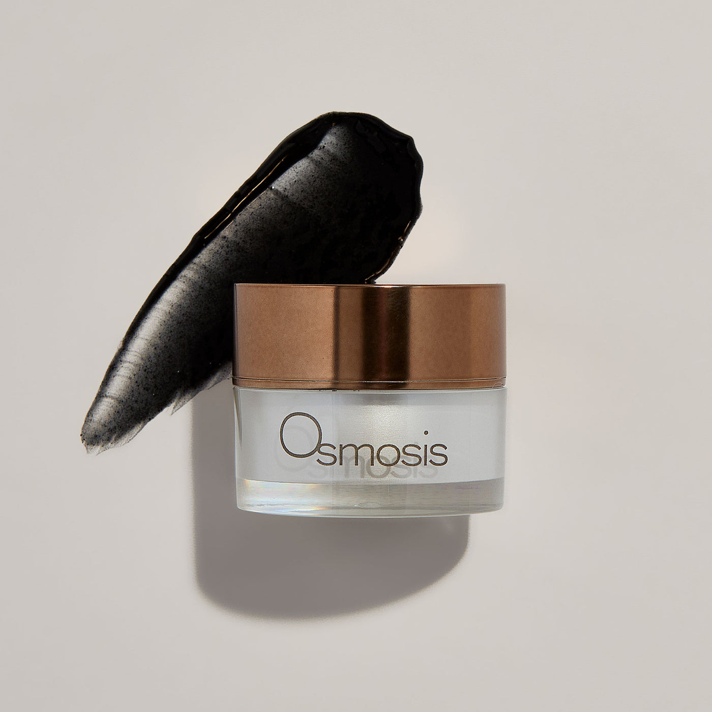 Osmosis Skincare jar with a black product smear on a light gray background