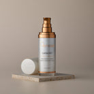 Skincare serum bottle with gold cap on a beige background