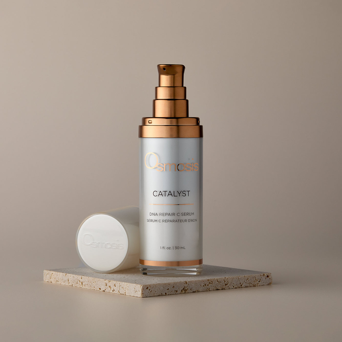 Skincare serum bottle with gold cap on a beige background