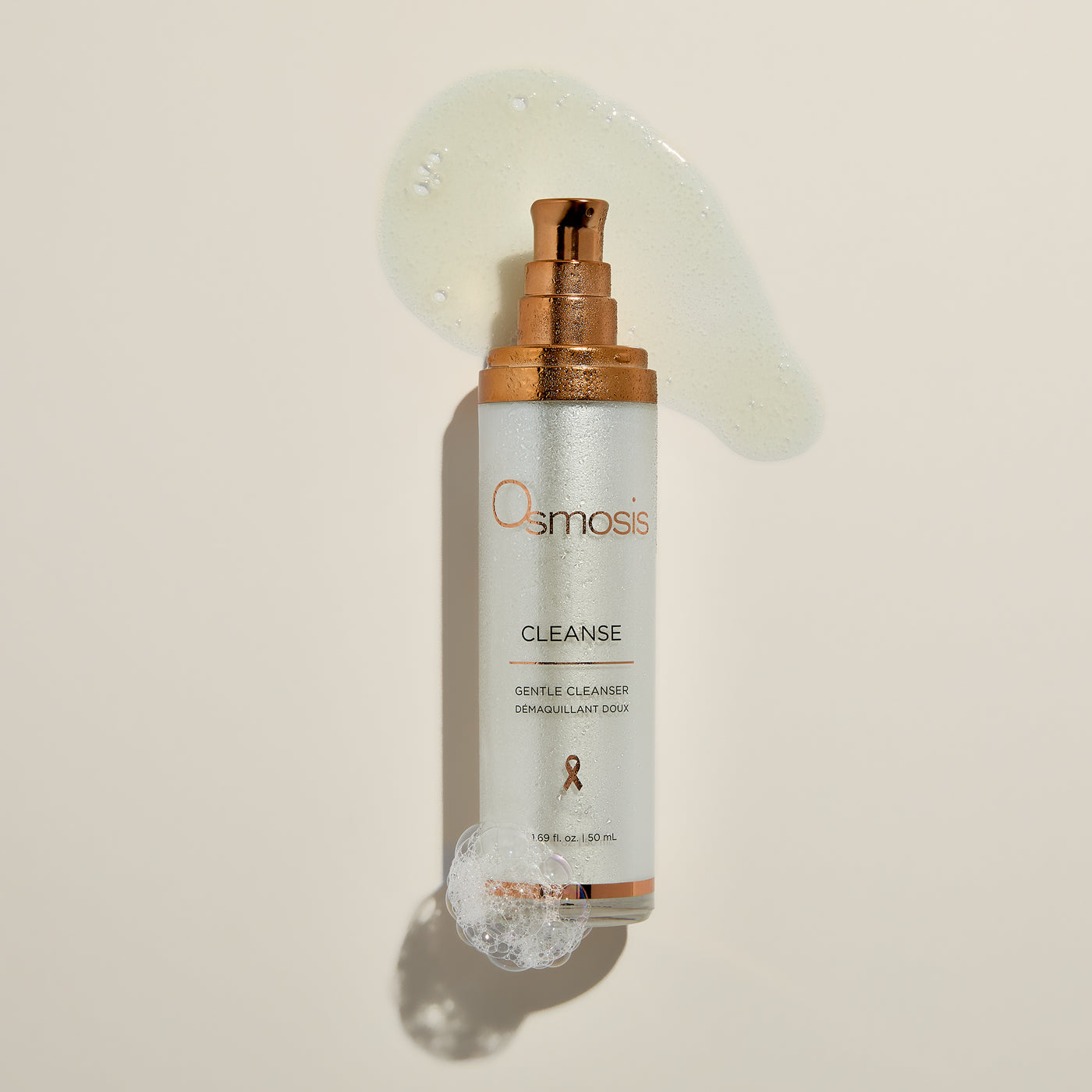 Osmosis skincare bottle with gold pump on a beige background
