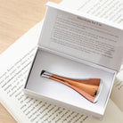 cool skin tool sitting inside its product box, lying atop an open book