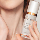 Osmosis Rescue skincare serum held by a hand with a neutral background