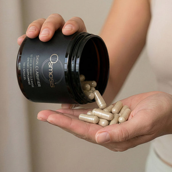 Person holding a container of Osmosis Skin Clarifier capsules.