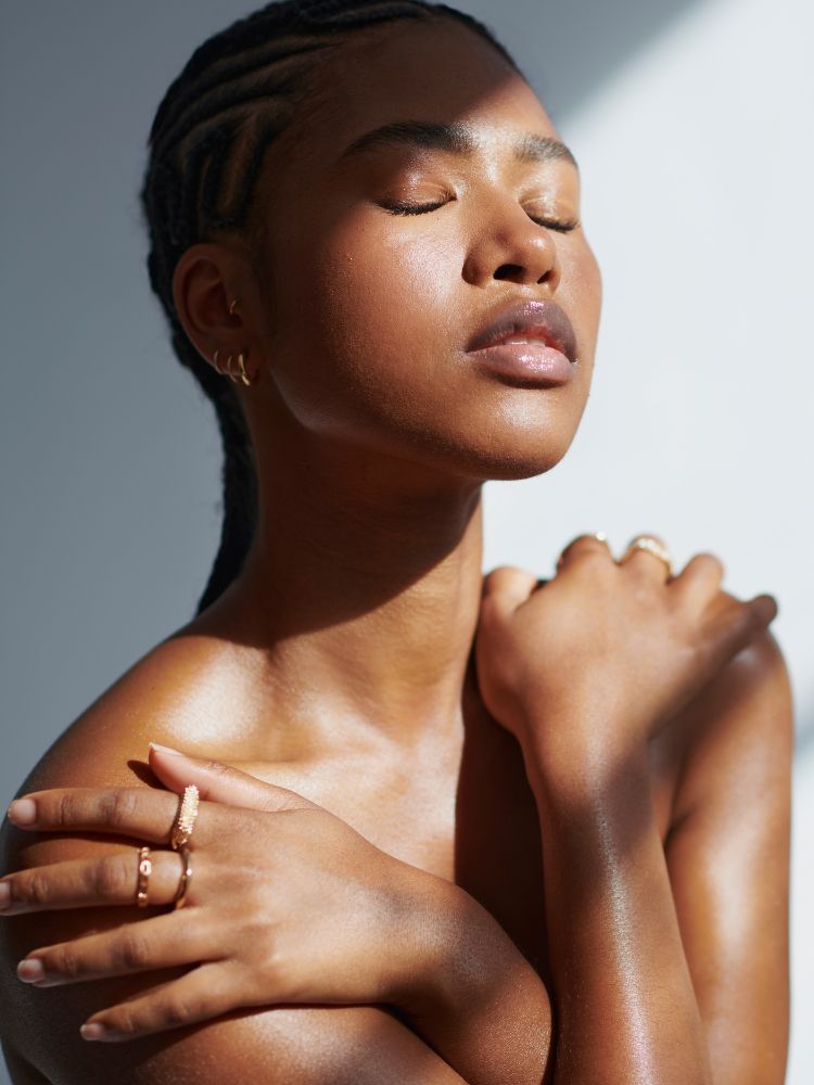 Woman with closed eyes, hands on shoulders, against a neutral background