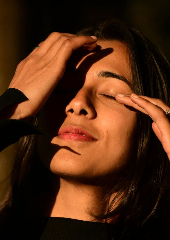 Woman with hands on her face in a dimly lit setting